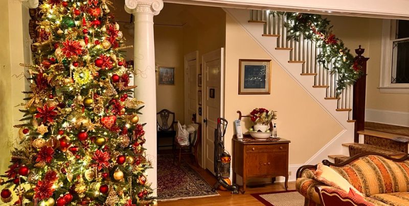 A lit-up Christmas tree and decorated stair banister at Bay Haven Inn of Cape Charles