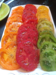 Red, green, and yellow sliced tomatoes on a plate