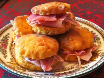 Sweet potato biscuits and Virginia ham on a floral print plate atop a red tablecloth. 
