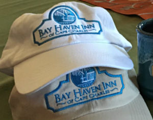 A white hat and a beige hat with blue logos and the text: Bay Haven Inn of Cape Charles.
