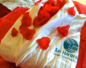 A white robe covered in red rose petals with the text: Bay Haven Inn of Cape Charles.