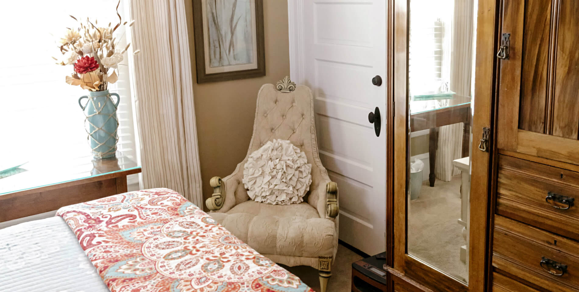 A beige comfortable chair with a throw pillow near the white door of a closet. 