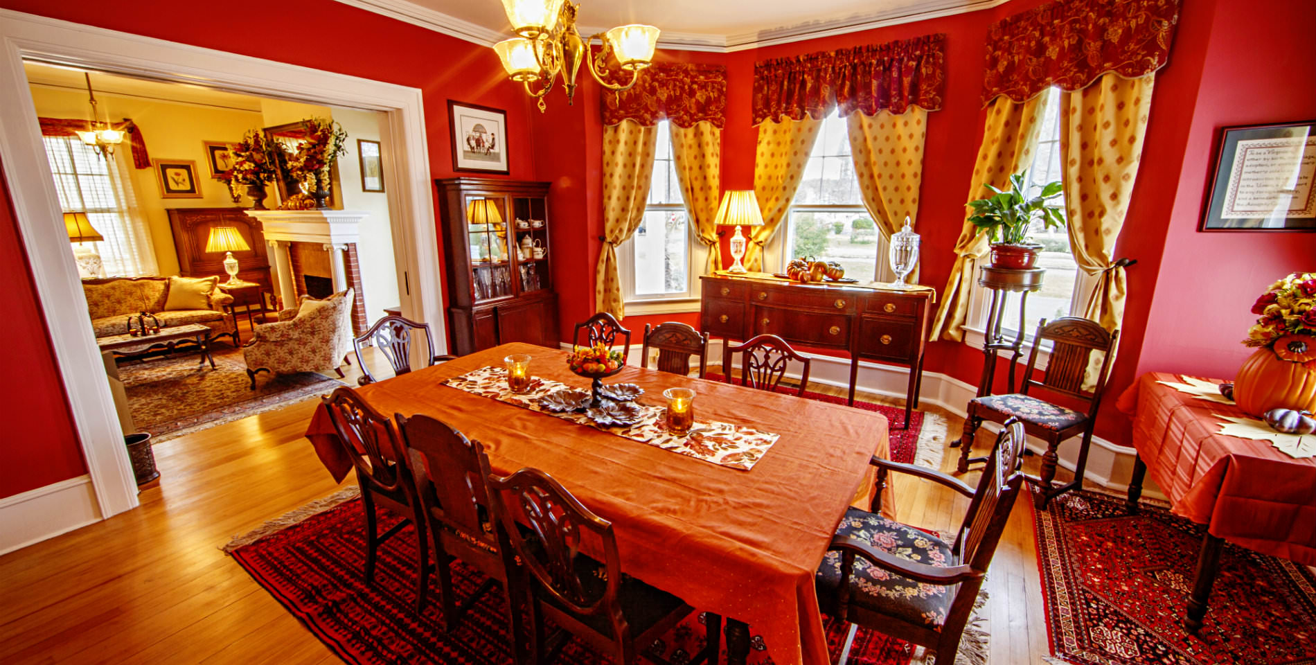 The ornately decorated dining room of the Inn, with cranberry red walls and golden brown hardwood flooring. 