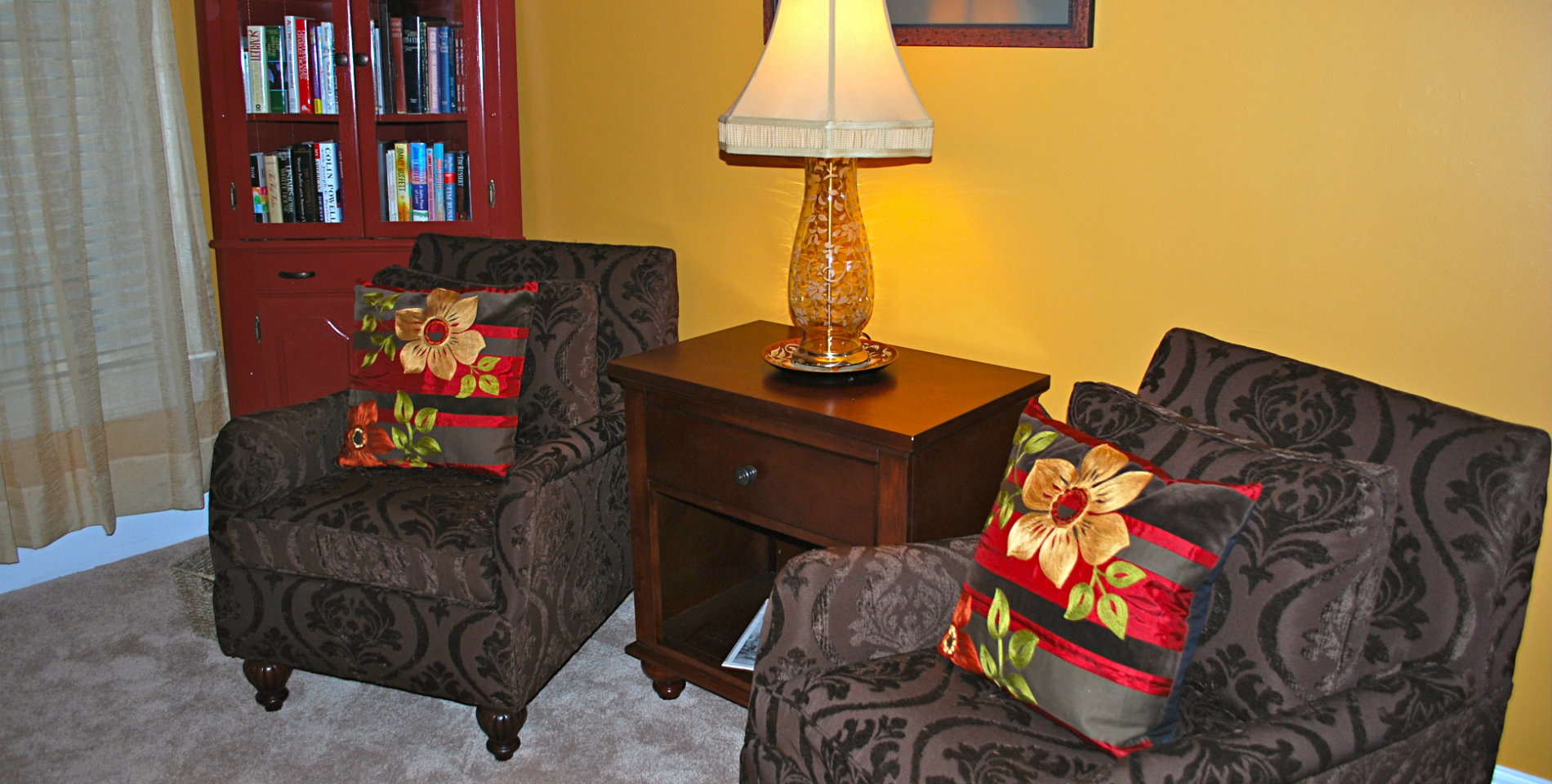 Two plush paisley patterned chairs with red and black striped throw pillows. 