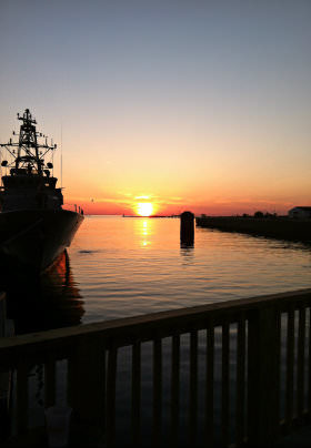 The sun sets over the blue water of the Bay, a crabbing vessel resting in the calm water. 