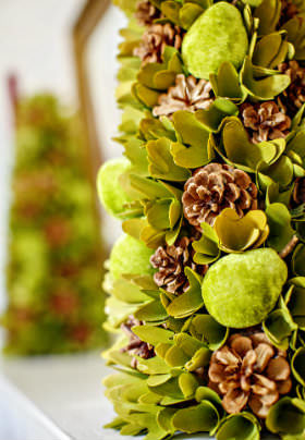 A beautiful, decorative stand of green leaves and brown pine cones with another stand in the background. 
